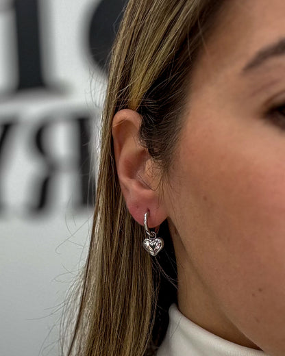 modelo usando brincos pendente coração prateado aço inox